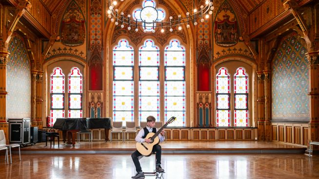 Junger Gitarrist spielt in der festlich beleuchteten Aula des Geschwister-Scholl-Gymnasiums